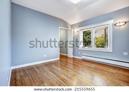 Empty bedroom with light blue walls and new hardwood floor
