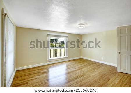 Bright empty room with two windows and new hardwood floor