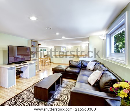 Mother-in-law apartment interior in light tones with black leather couch and zebra rug