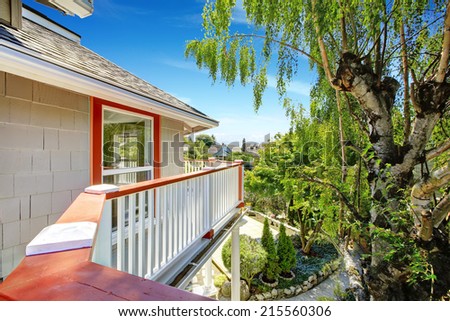 Wrap-around walkout deck with white railings and orange trim overlooking backyard garden