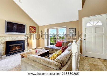 House interior with high vaulted ceiling. Living room with fireplace, tv and comfortable sofa. Entrance hallway with railings and tile floor
