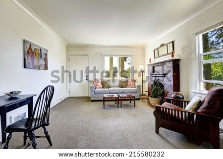 Simple room with brick fireplace and beige carpet floor. Old house interior