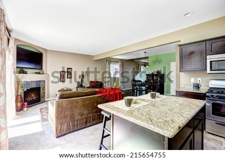 House interior with open floor plan. View of kitchen island with granite top and living room with fireplace