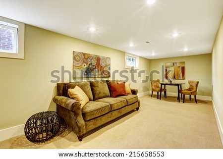 Basement room interior with comfortable sofa, table and chairs