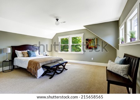 Bedroom interior with beige carpet floor and green walls. Furnished with wooden bed and  bench