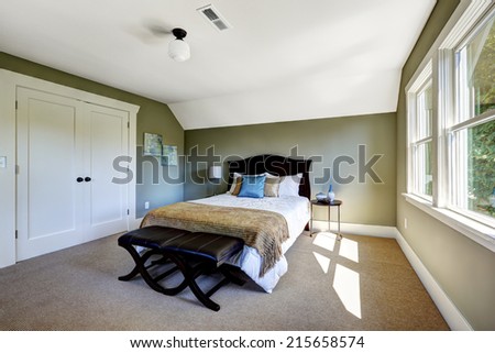 Bedroom interior with beige carpet floor and green walls. Furnished with wooden bed and chairs