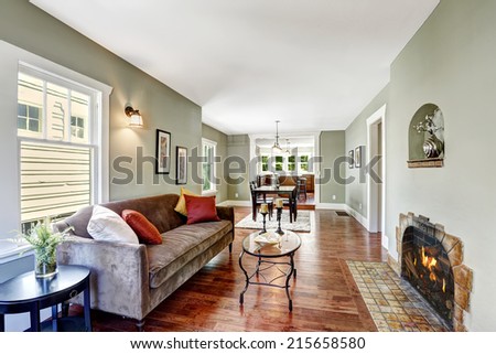 House interior in soft mint color with hardwood floor, brown soft couch and glass top coffee table