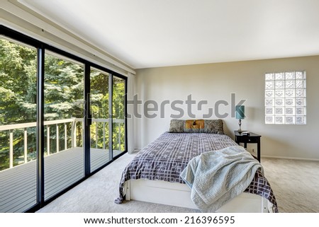 White refreshing master bedroom interior with walkout deck and glass block window