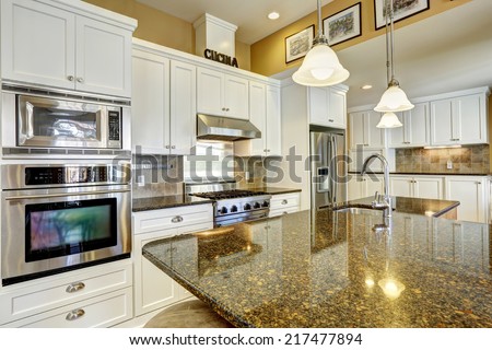 Bright kitchen room with granite tops, kitchen island and white cabinets