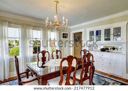 Bright dining room with rich carved wood dining table set and white storage cabinets