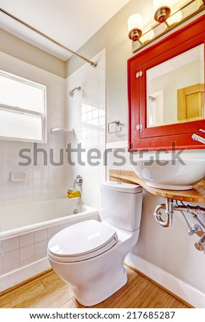 Refreshing bathroom interior. Red cabinet with mirror and white vessel sink