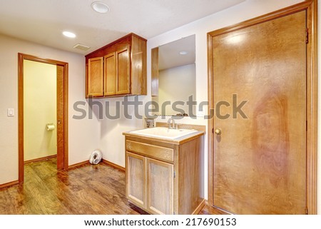 Empty bathroom with hardwood floor, old vanity cabinet and hanging cabinet