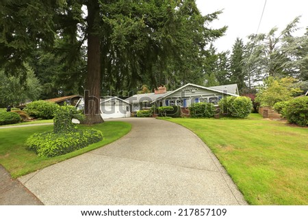 House exterior with garage and driveway view. Lawn with trimmed bushes