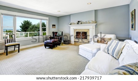 Light blue living room with white sofa, armchair and leather chair and cozy fireplace