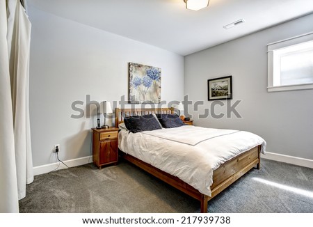 Simple bedroom interior in light grey tones with wooden bed and nightstands