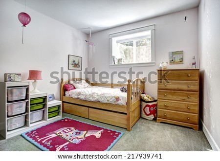 Cozy kids room with rustic bed and dresser. Cheerful red rug on carpet floor