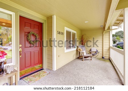 Spacious entrance porch with red door and wooden chair