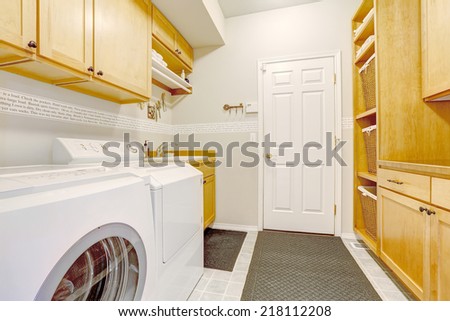 Bright laundry room with storage combination and white washer and dryer. New house interior