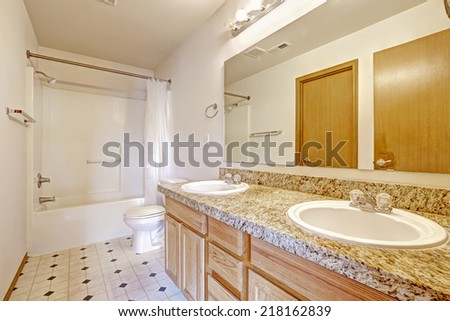 Simple bathroom interior with linoleum floor, wooden cabinet with mirror and white bath tub with curtains