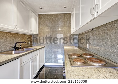 White kitchen cabinets with grey tile wall trim and tile floor
