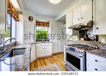 Kitchen area with white cabinets, granite tops and steel stove with hood