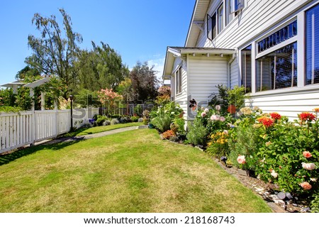 Front yard landscape with flowers and white fence