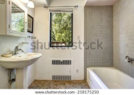 Old bathroom in white and grey color with washbasin stand, cabinet with mirror and bath tub