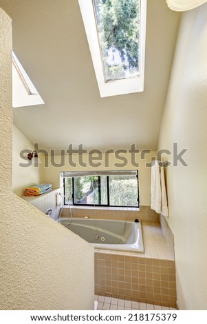 Bathroom with window, high vaulted ceiling  and skylights. Bath tub with tile trim