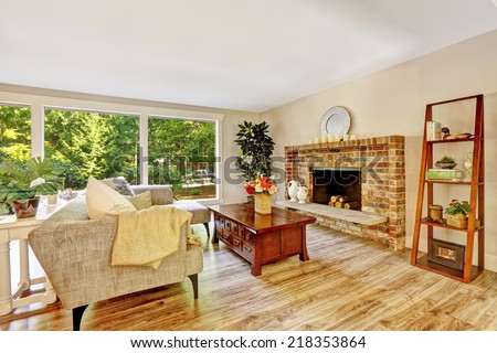 Spacious bright living room with brick fireplace, couch, wooden coffee table and glass wall