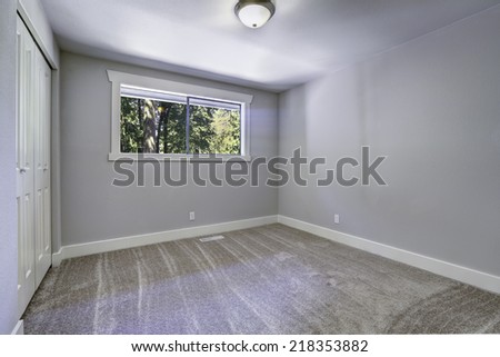 Light blue empty room with brown carpet floor. Room has closet and small room