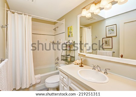 White refreshing bathroom with tile wall trim and white curtains. White bathroom cabinet with beautiful sink and large mirror