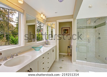 Spacious bright bathroom with white storage combination and glass door shower