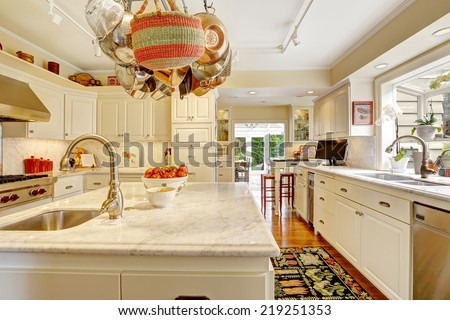 White kitchen with white granite tops, island and hanging pot rack