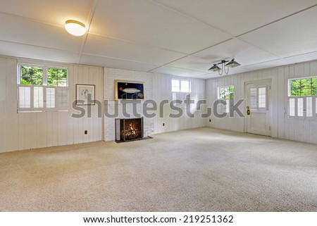 Spacious empty basement room with brick fireplace