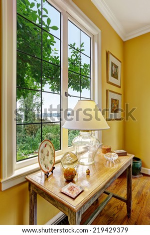Bright yellow room with large window and antique table with decorative elements