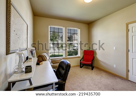 Simple office room with white desk. Bright red chair in the corner