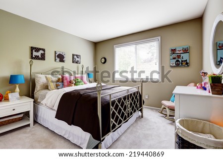 Bedroom interior. Iron frame bed with colorful pillows and toys