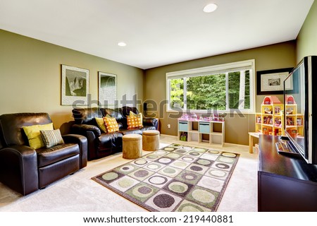 Green room with black leather couch and armchair. Playhouse for kids