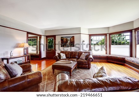 Bright luxury family room with rich leather couches and sitting area by the windows