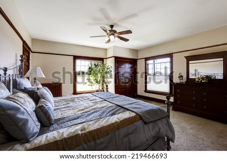 Master bedroom with iron frame bed and green tree in the corner