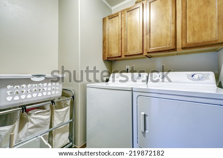 Laundry room with cloth bags on rack, white dryer and washer and wooden cabinets