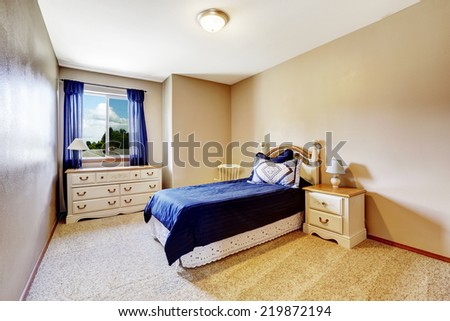 Ivory bedroom interior with soft carpet floor. Wooden old style furniture set with navy color bedding and curtain