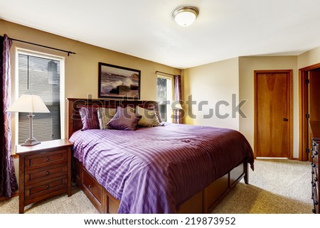 Master bedroom interior. Rich furniture set with bright purple bedding and pillows
