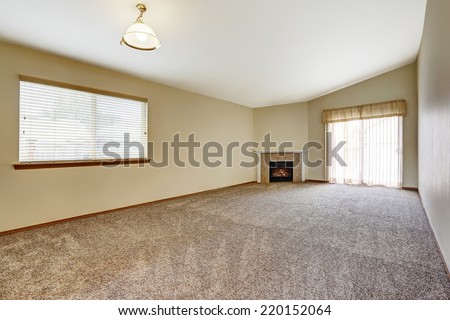Spacious empty living room in ivory color with fireplace. Room has walkout deck