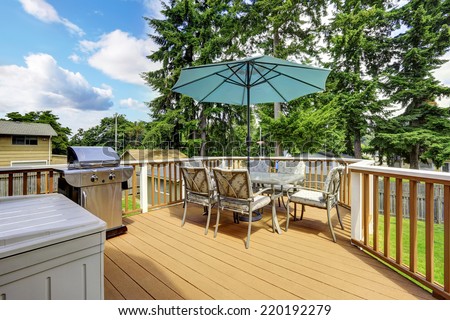 Walkout deck in brown and white trim. Patio table set with umbrella and jacuzzi