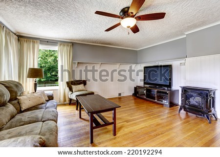 Living room interior in old house. Comfortable sofa with wooden coffee table, TV and antique stove