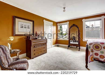 Brown bedroom with carved wood bed, antique mirror and cabinet