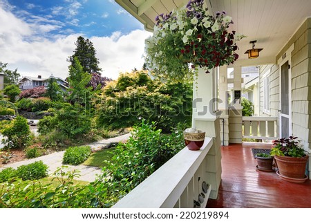 Entrance porch in old house with flower pots. View of walkway and front yard landscape