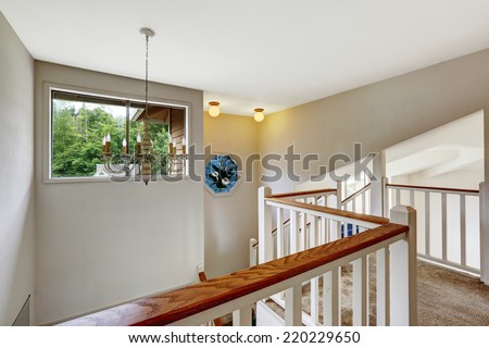 Empty house interior with high vaulted ceiling. Upstairs deck with carpet floor and white railings with brown trim