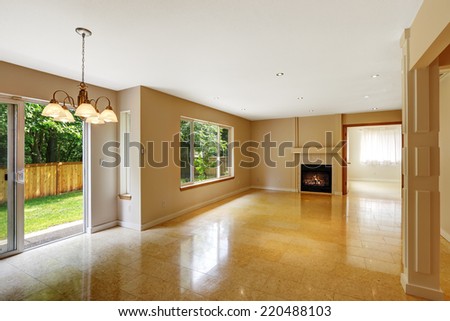 Empty living room with shiny marble tile floor and fireplace. Room has exit to backyard area